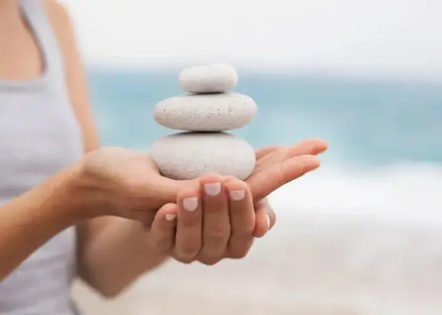 A person holding rocks in their hands on the beach